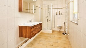 A modern bathroom with a wooden vanity, a glass shower enclosure, and a toilet. - mit Blick auf das Wasser by Interhome (Geigant)