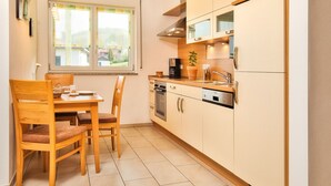 A compact kitchen with a dining area, featuring a window, wooden cabinets, and basic appliances. - mit Blick auf das Wasser by Interhome (Geigant)