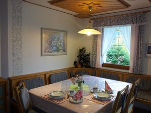 A dining room with a table set for four, chairs, a ceiling fan, a window with curtains, and a painting on the wall. - Apartment Anna by Interhome (Flattach)