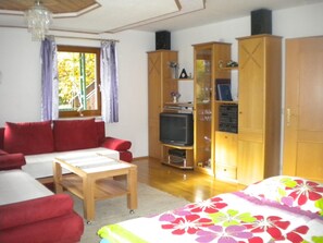 A living room with a red sofa, a wooden table, a television, and wooden cabinets. - Apartment Anna by Interhome (Flattach)