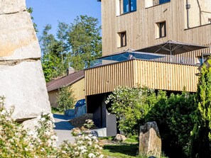A modern building with a wooden facade, a stone structure in the foreground, and a clear sky. - mit Sauna by Interhome (Breitenberg)