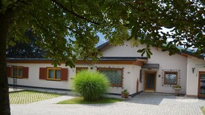 A building with a paved courtyard, a large bush, and a small garden area. - Erna Angermaier by Interhome (Flattach)