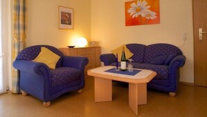 A living room with two blue armchairs, a small wooden table, and a painting of daisies on the wall. - FEWO Hortensie by Interhome (Bruttig-Fankel)
