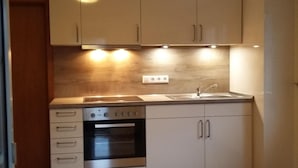 A compact kitchen with a built-in oven, a sink, and light-colored cabinets. - FEWO Hortensie by Interhome (Bruttig-Fankel)
