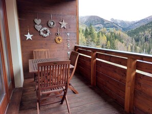 A wooden deck with a table and chairs, a wooden railing, and a view of a mountainous landscape. - Rosie desing skipist by Interhome (Bad Kleinkirchheim)