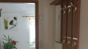 Ein Flur mit einem Holzschrank, einem Spiegel und einer Topfpflanze.