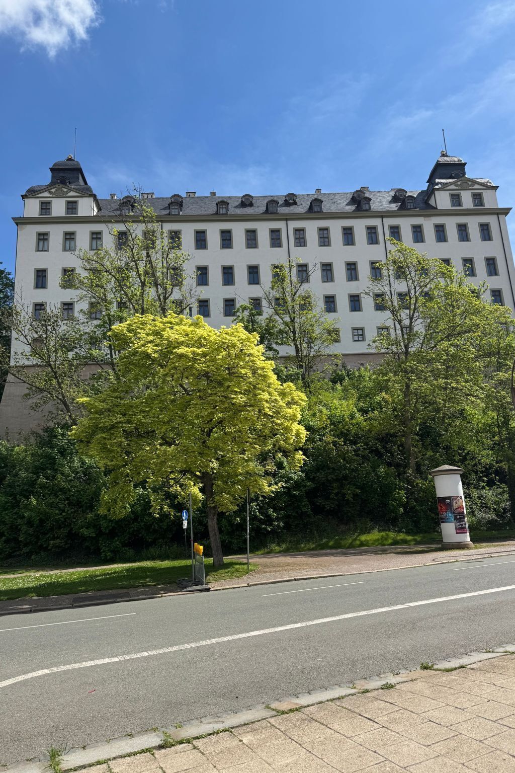Ein mehrgeschossiges Gebäude mit einer symmetrischen Fassade, großen Fenstern und einem zentralen Eingang.