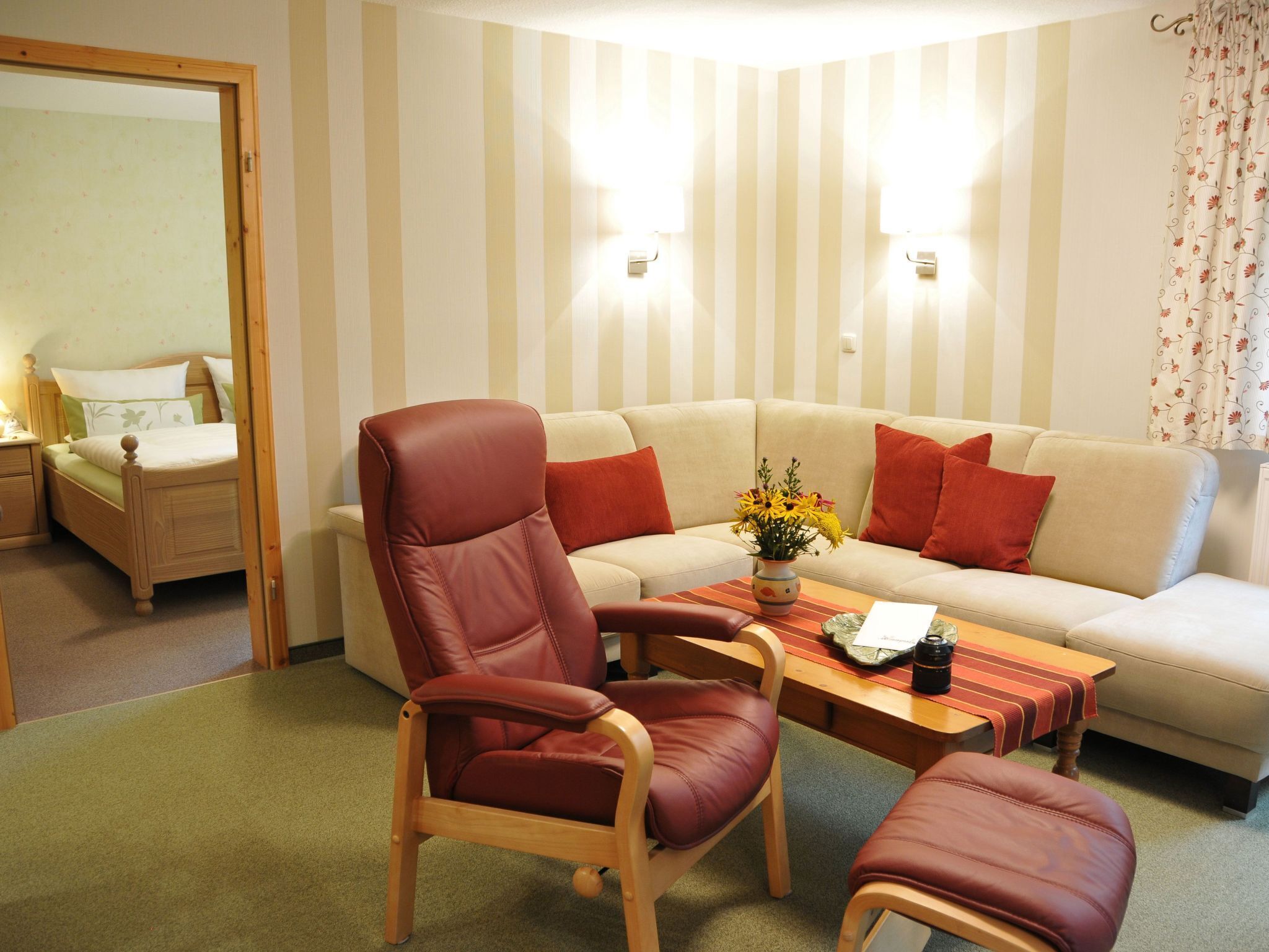 A living room with a sofa, two armchairs, a coffee table, and a bed.