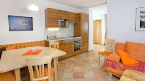 Ett kompakt bostadsutrymme med ett litet kök, matplats och sittgrupp.