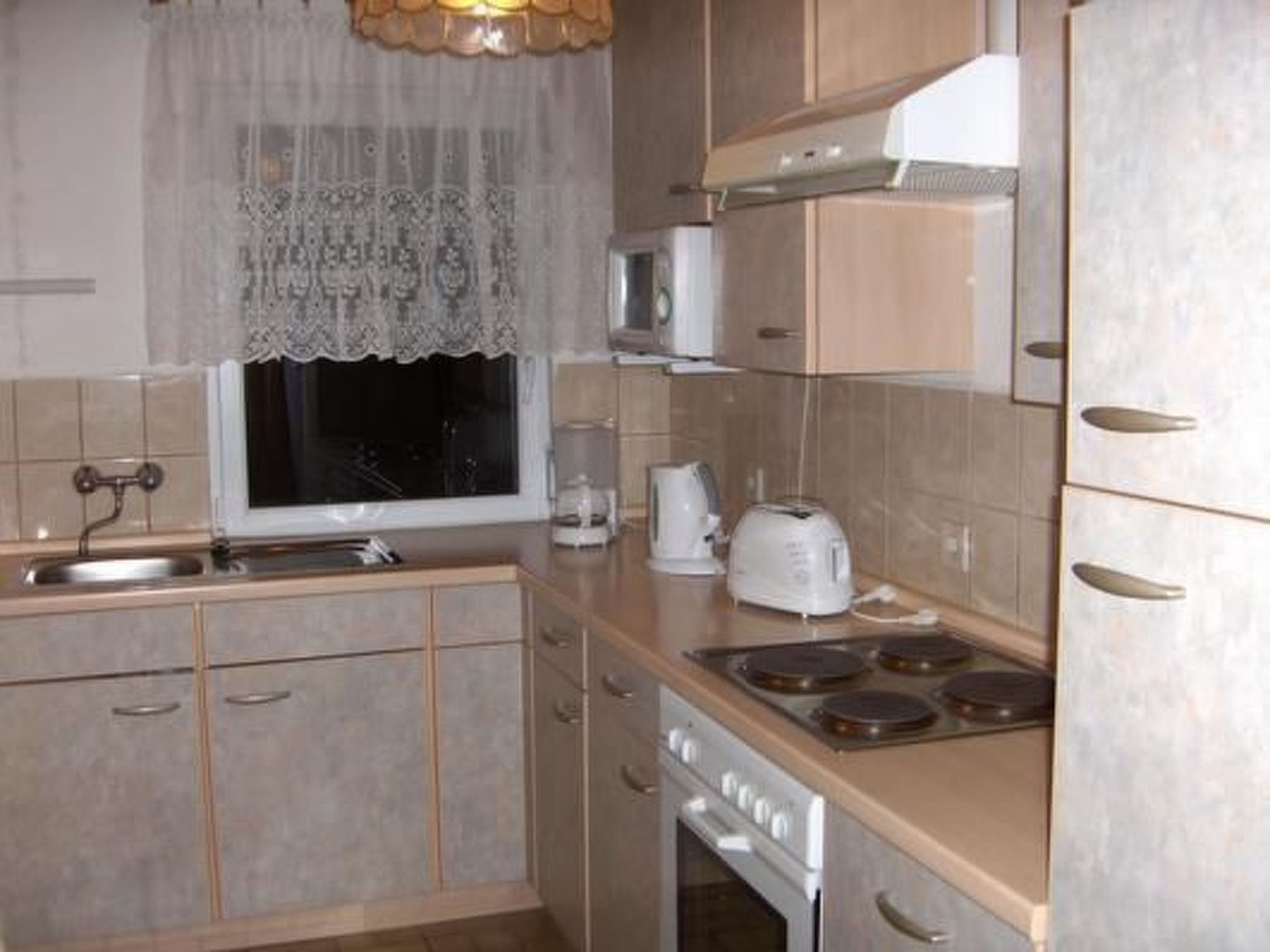 A kitchen with a window, a sink, a stove, a microwave, and cabinets.