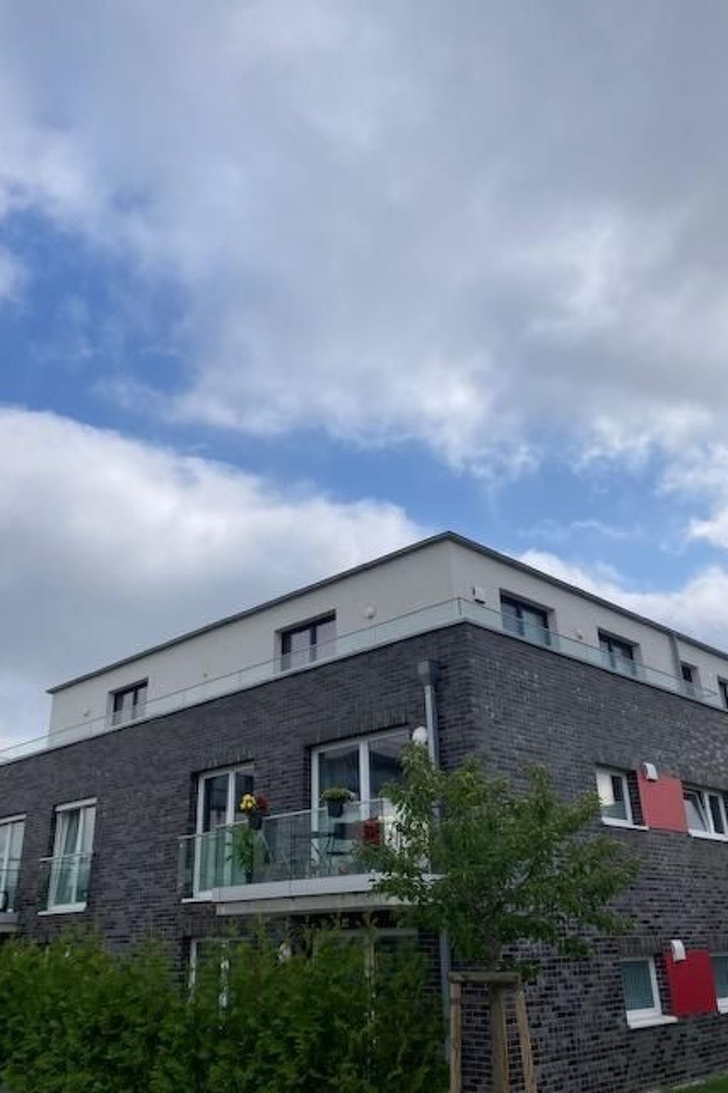Un bâtiment moderne à deux étages, doté d’un toit plat, de grandes fenêtres et d’un balcon.