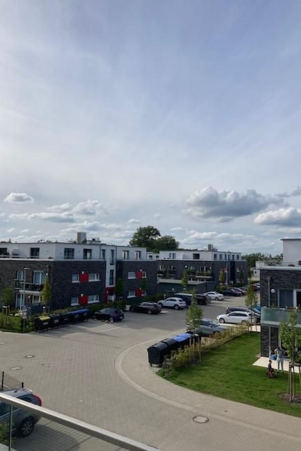 Un moderno complejo de apartamentos con varios edificios, una zona de estacionamiento y un área verde.