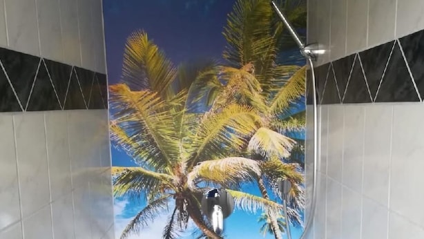 Ein Badezimmer mit Wandmalerei einer Strandlandschaft, inklusive Palmen und blauem Himmel.