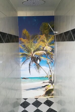 Ein Badezimmer mit Wandmalerei einer Strandlandschaft, inklusive Palmen und blauem Himmel.
