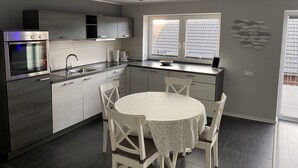 Eine moderne Küche mit Einbauofen, Spüle und Essbereich mit rundem Tisch und weißen Stühlen.
