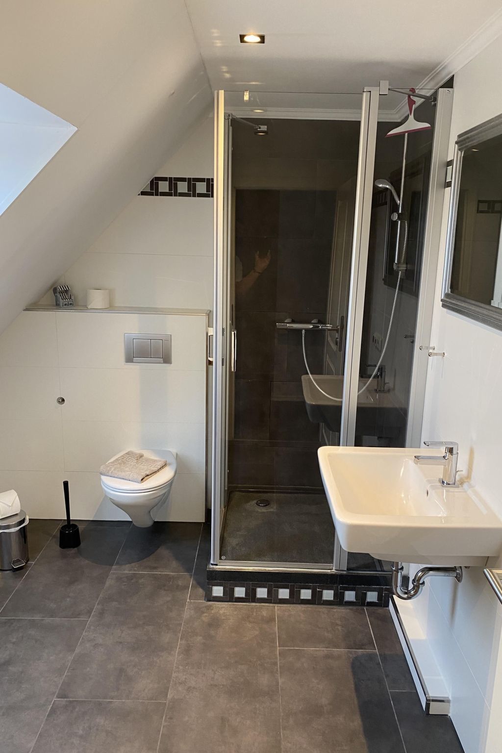 A modern bathroom with a shower, toilet, and sink.