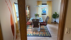 A dining area with a table set for four, surrounded by wicker chairs and a patterned rug. - Mayer in Oberkirch by Interhome (Oberkirch)
