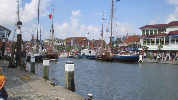 A harbor with boats docked, a cobblestone walkway, and buildings with cafes. - Apartment Minimi by Interhome (Büsum)