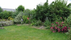 A garden with a variety of plants and flowers, a wooden fence, and a grassy lawn. - Apartment Minimi by Interhome (Büsum)