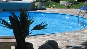 A swimming pool with a tiled deck, a potted plant, and decorative stones. - mit beheiztem Pool in Flattach by Interhome (Flattach)