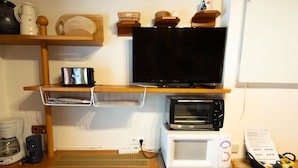 A compact kitchenette with a microwave, toaster, coffee maker, and a flat-screen TV on a wooden shelf. - mit beheiztem Pool in Flattach by Interhome (Flattach)