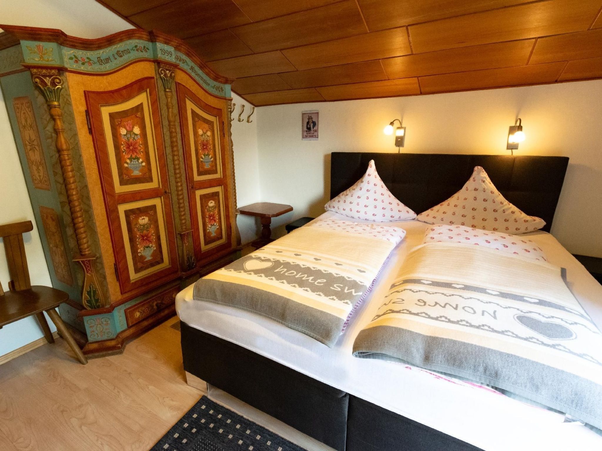 Une chambre avec deux lits, des têtes de lit en bois, une armoire décorative et des lampes fixées au mur.