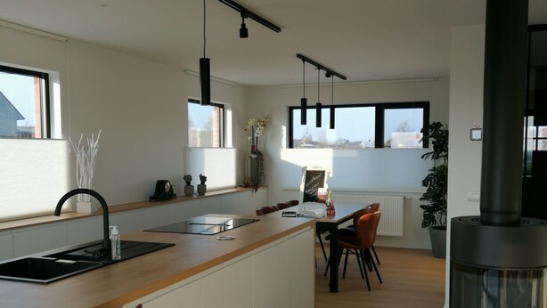 Una cucina moderna con isola centrale, zona pranzo con sedie e un'ampia finestra che offre luce naturale.