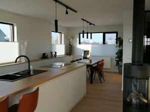 A modern kitchen with a central island, a dining area with chairs, and a large window providing natural light. - Ferienvilla "Wellness Akkerland" by Interhome (Zonnebeke)