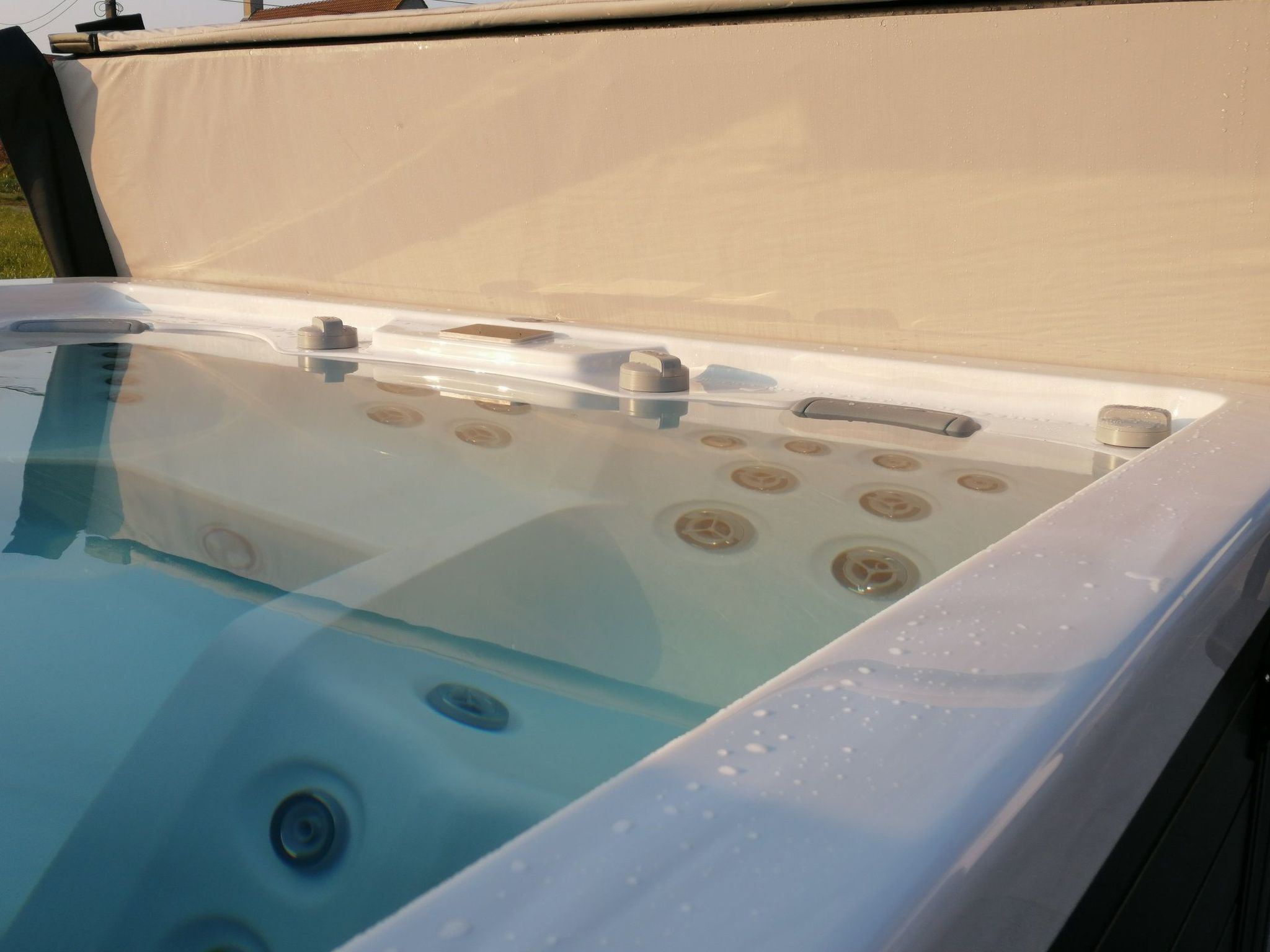 A hot tub with a transparent cover, multiple jets, and a drain.