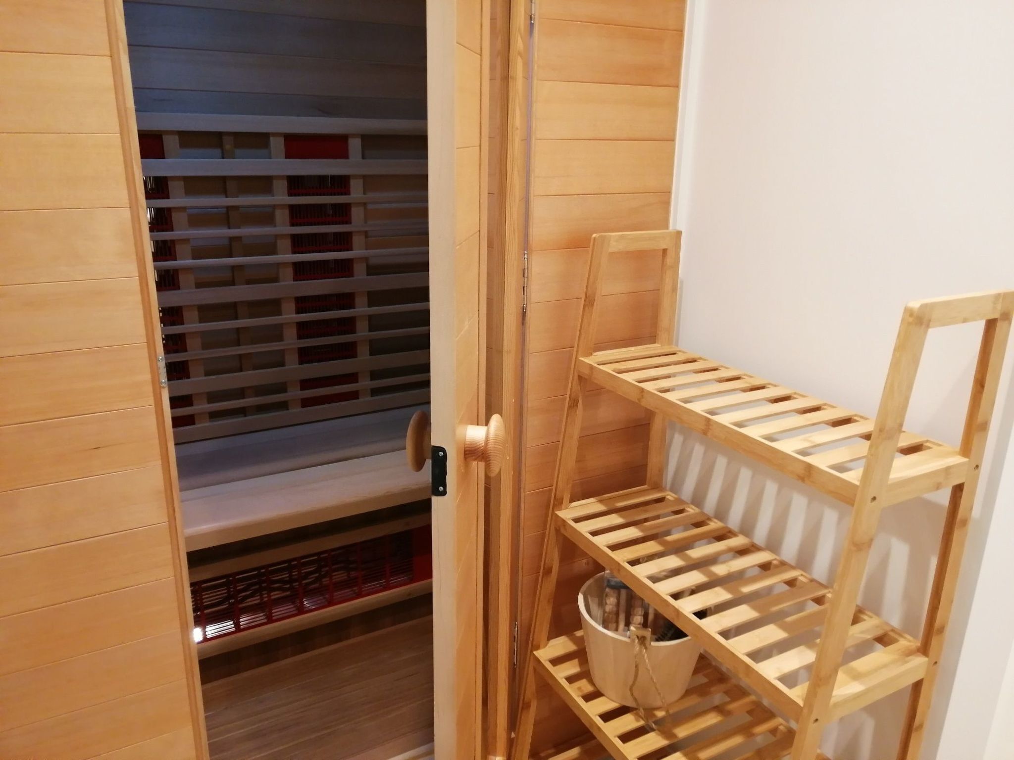 A wooden closet with shelves and a hanging rod, a wooden door, and a wooden floor.