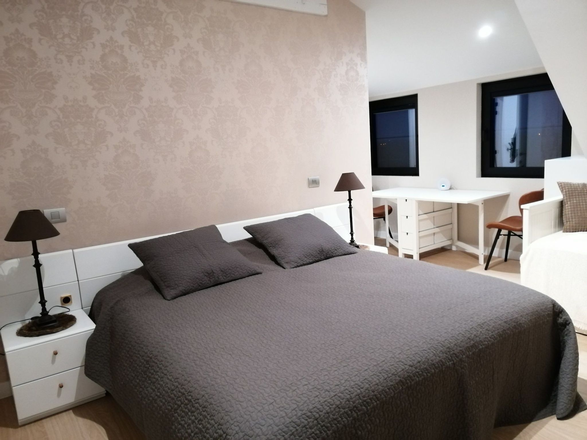 A modern bedroom with a large bed, a desk, and a chair.