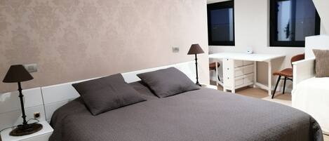 A modern bedroom with a large bed, a desk, and a chair.