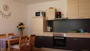 Una cocina compacta con armarios de madera, microondas, cafetera y horno.