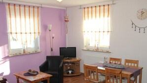 Una sala de estar con una mesa de madera, sillas, un televisor y un sofá.