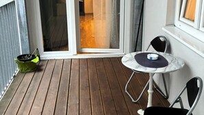 A wooden deck with a sliding glass door leading to a room, a small round table, and two chairs. - Wohnen am Augarten by Interhome (Vienna)