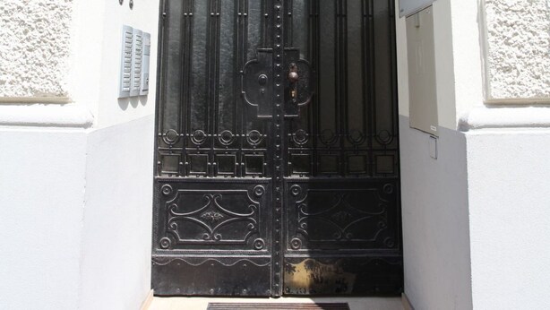 A black wrought iron gate with a number plate indicating "15" and a small sign above it. - Wohnen am Augarten by Interhome (Vienna)