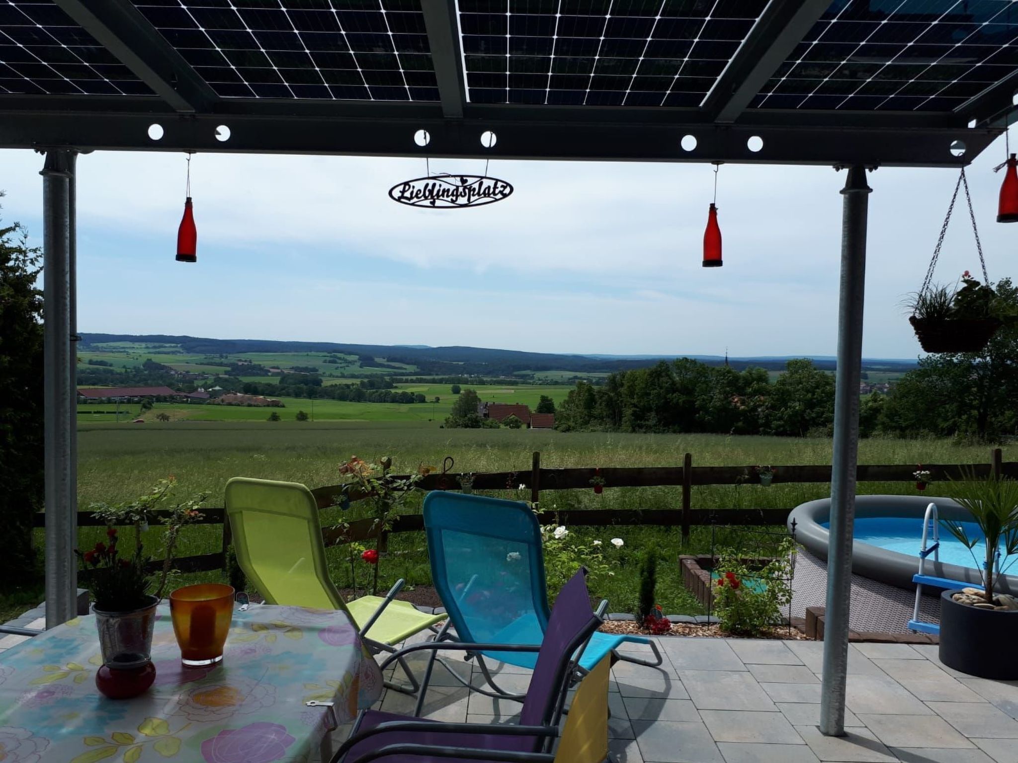 Un espacio de estar al aire libre cubierto con vistas a una piscina y al campo.
