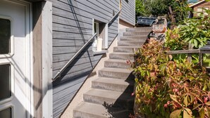 Eine Betonstairtreppe führt zu einer Holztür mit einem Metallgeländer.
