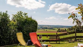Un espacio al aire libre con césped, dos sillones de relax y un banco de madera.