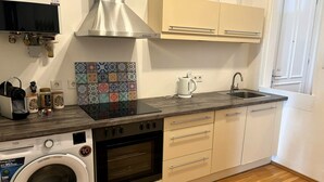 Een kleine keuken met een wasmachine, oven en koffiezetapparaat op het aanrecht.