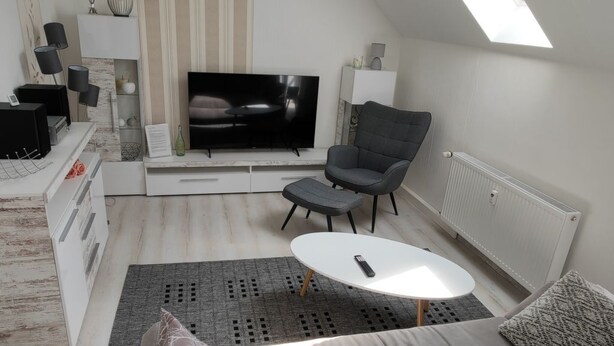 A modern living room with a flat-screen TV, grey sofa, and a small round table. - Urlaubszuhause by Interhome (Naundorf)