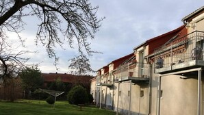 A residential building with a red roof, multiple balconies with metal railings, and a well-maintained lawn. - Urlaubszuhause by Interhome (Naundorf)
