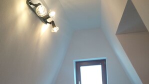 A small, sloped room with a single bed, a window, and a wall-mounted light fixture. - Ferien- und Monteurwohnung Nepperwitz Süd by Interhome (Bennewitz)