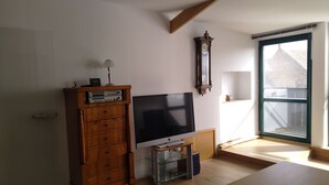 A living room with a flat-screen TV, wooden cabinet, and a large window. - Ferien- und Monteurwohnung Nepperwitz Süd by Interhome (Bennewitz)