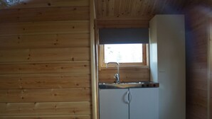 A compact kitchen with wooden walls, a window above the sink, and a refrigerator. - Järvstuga by Interhome (Arvidsjaur)