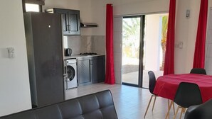 Un salon moderne avec un canapé en cuir noir, une table basse en verre et un coin repas agrémenté de rideaux rouges et d’une table.