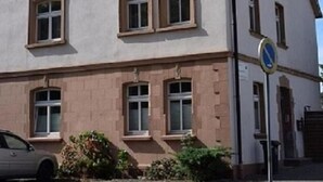 Un edificio de dos pisos con fachada simétrica, que presenta una entrada central con una puerta y ventanas a ambos lados.