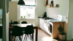 Una cocina moderna con zona de comedor, suelo de madera y una lámpara colgante.