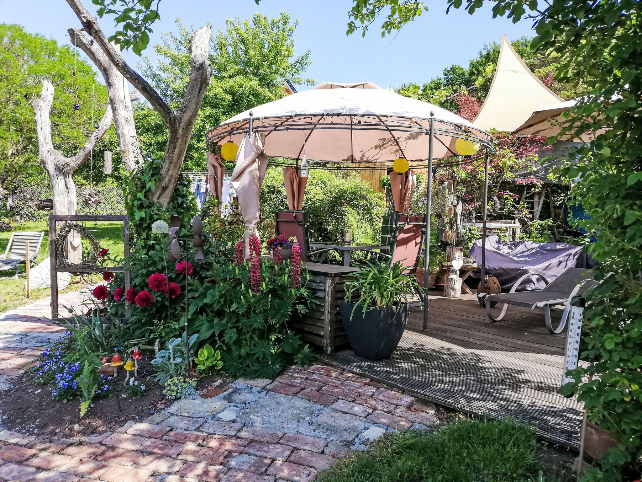 A garden with a gazebo, potted plants, and a brick pathway.