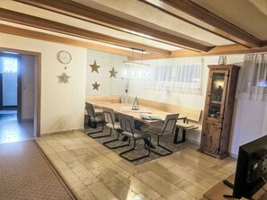 Une salle de conférence avec une table en bois, six chaises, une horloge et des étoiles décoratives sur le mur.